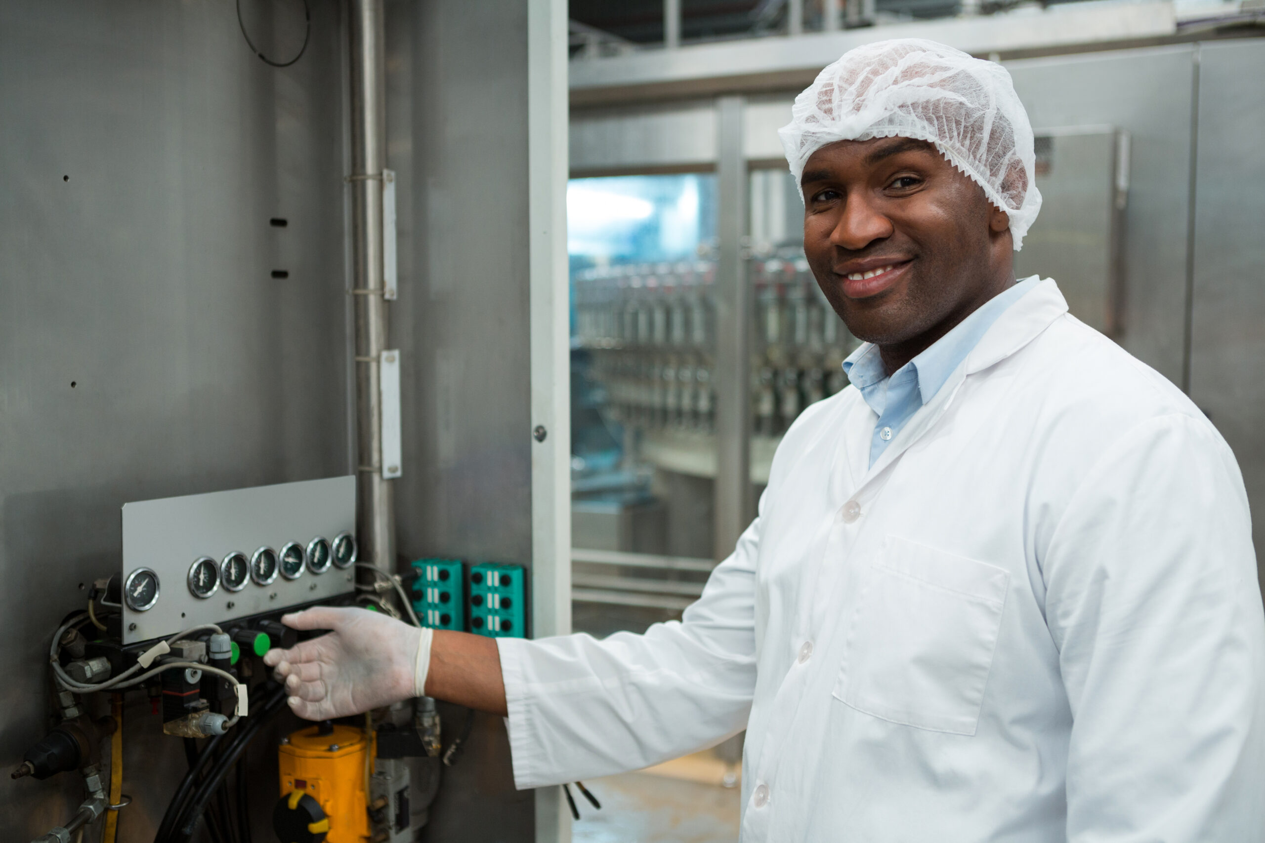 Portrait of confident male worker operating machine in juice factory