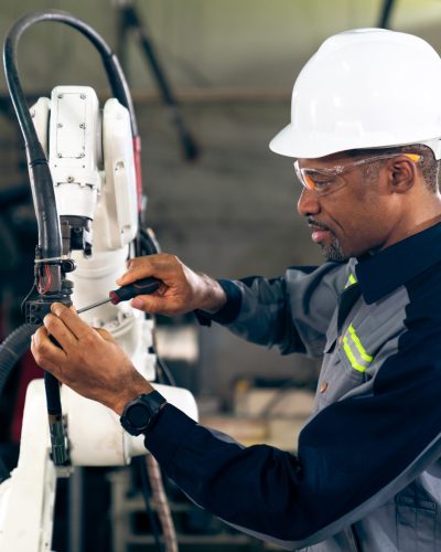 African American factory worker working with adept robotic arm