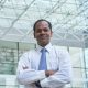 Smiling Indian businessman standing with his arms crossed and looking at camera