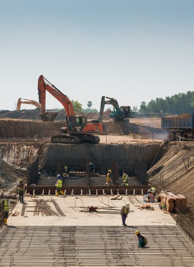 A close shot of heavy machines and construction workers working on a building